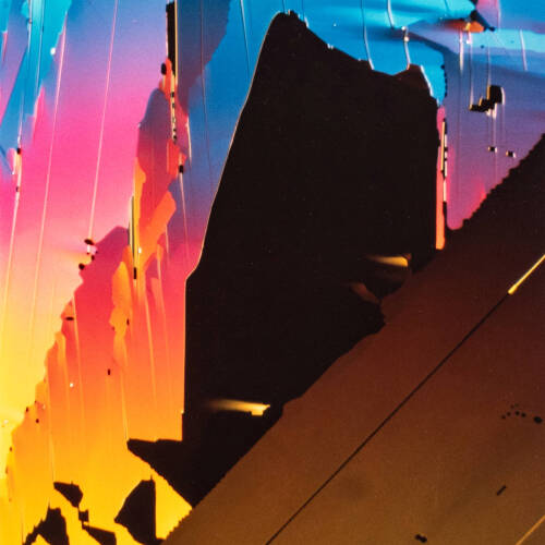 Highly colorful photograph of the side of a building with rainbow colors being reflected.